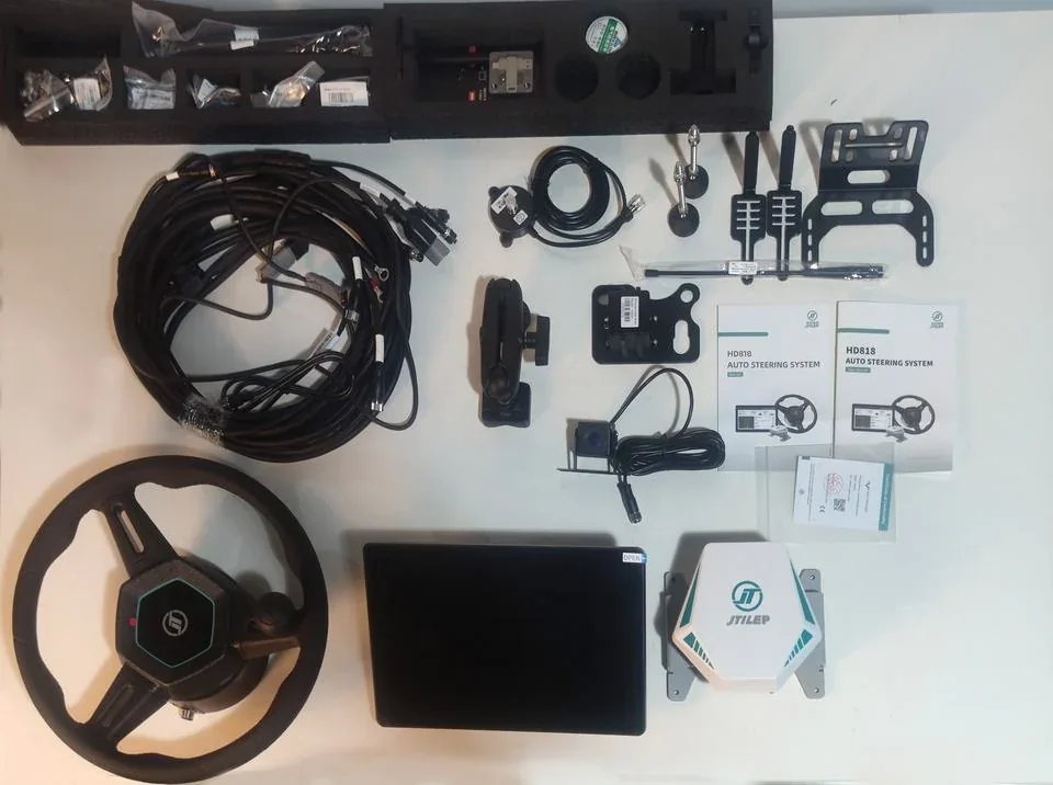 HD818 kit contents laid out: steering wheel assembly, display terminal, GNSS receiver, wiring harness, brackets, antenna and documentation